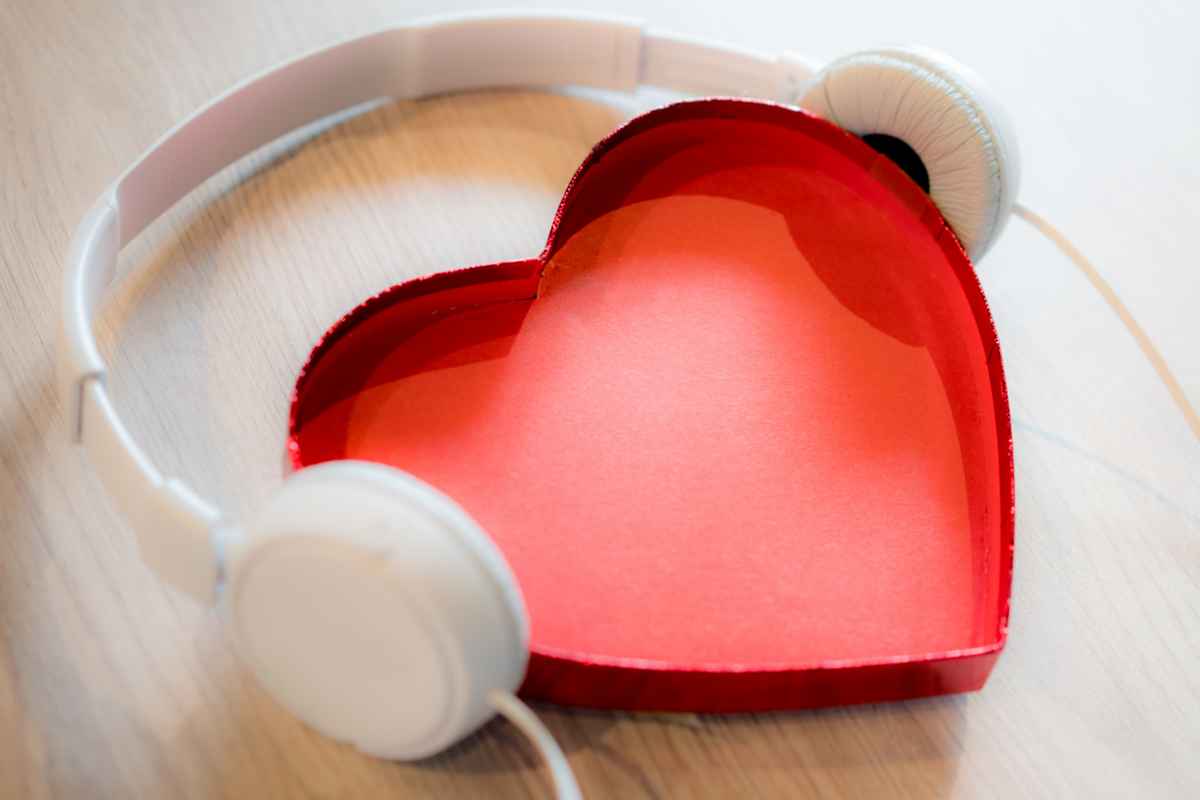 Scatola di cartone a forma di cuore rosso con cuffie bianche per ascoltare musica